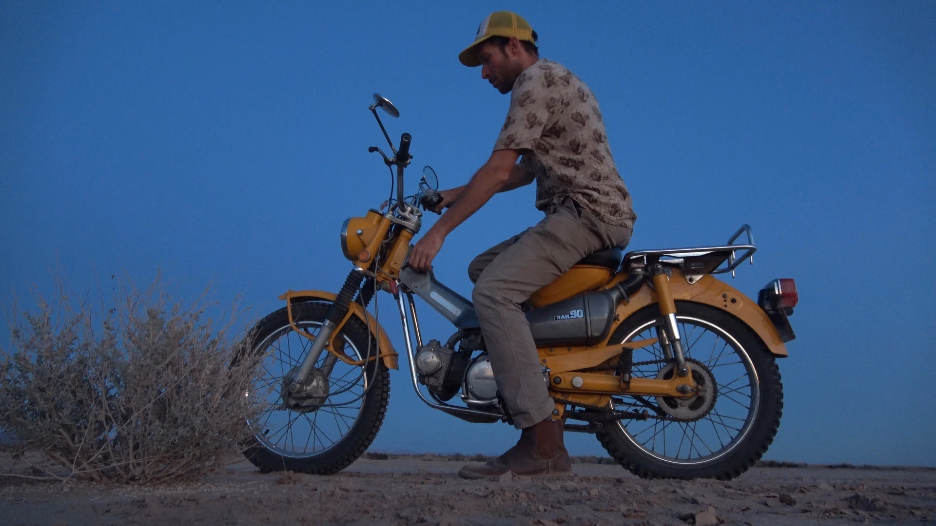 A rider on a yellow motorcycle against a blue sky