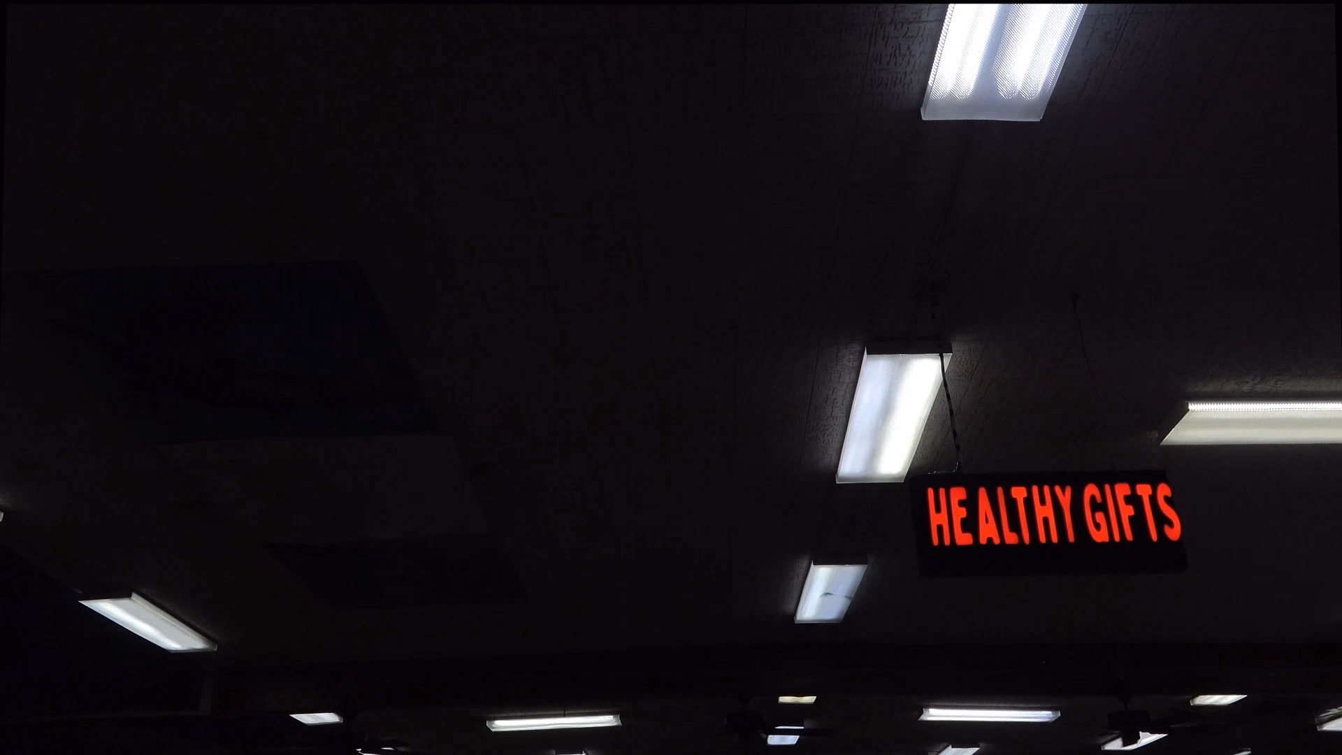 Fluorescent lights and a red Healthy Cuts sign in a dark interior