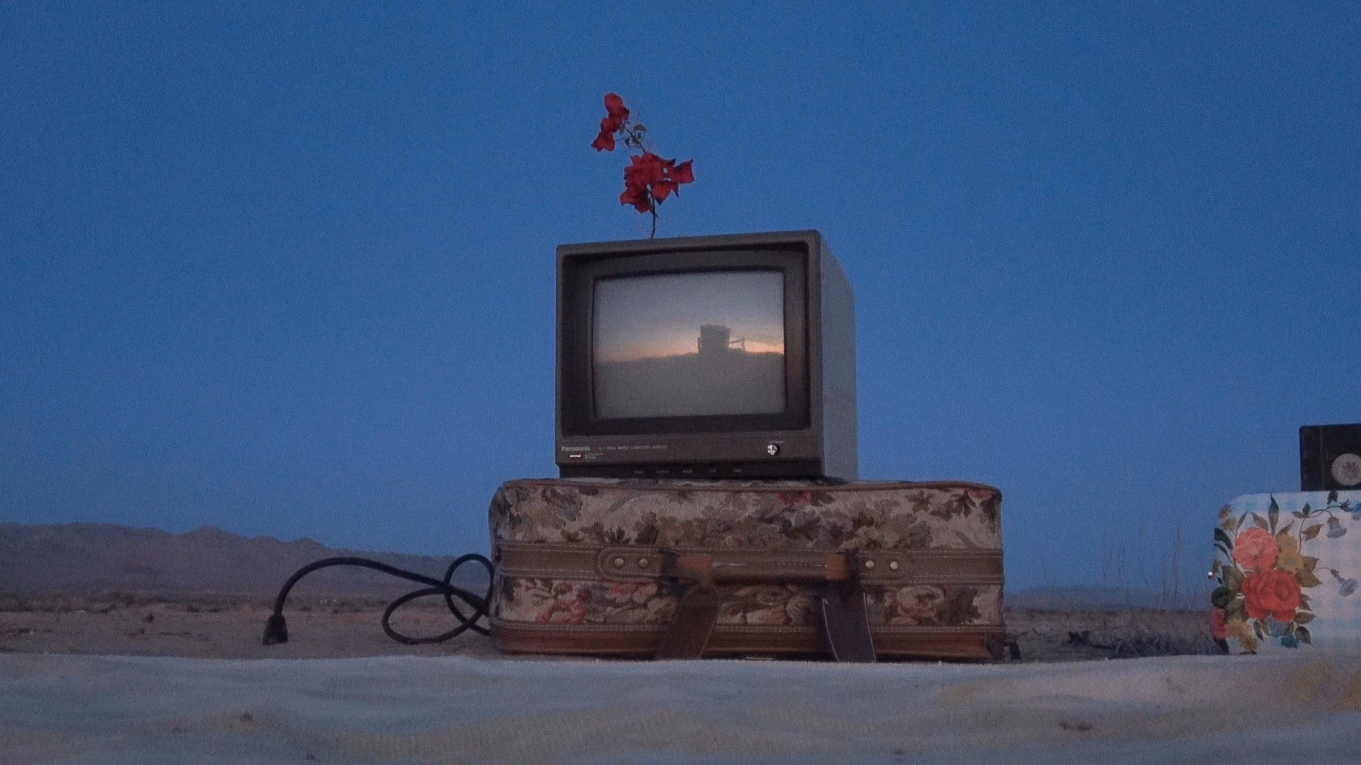 A television on stacked cases in the desert at dusk