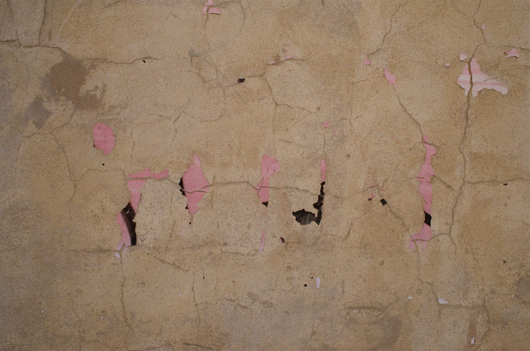 Cracked ochre plaster with fragments of pink paint