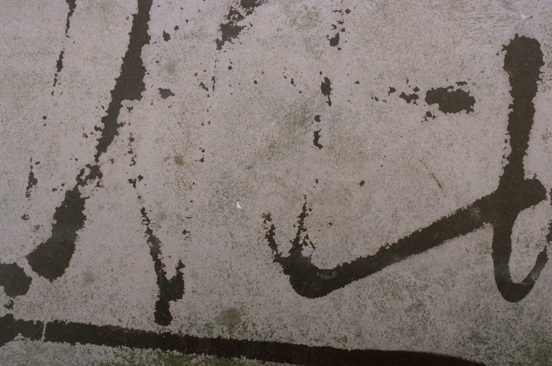 Dark curved marks across a pale, textured surface