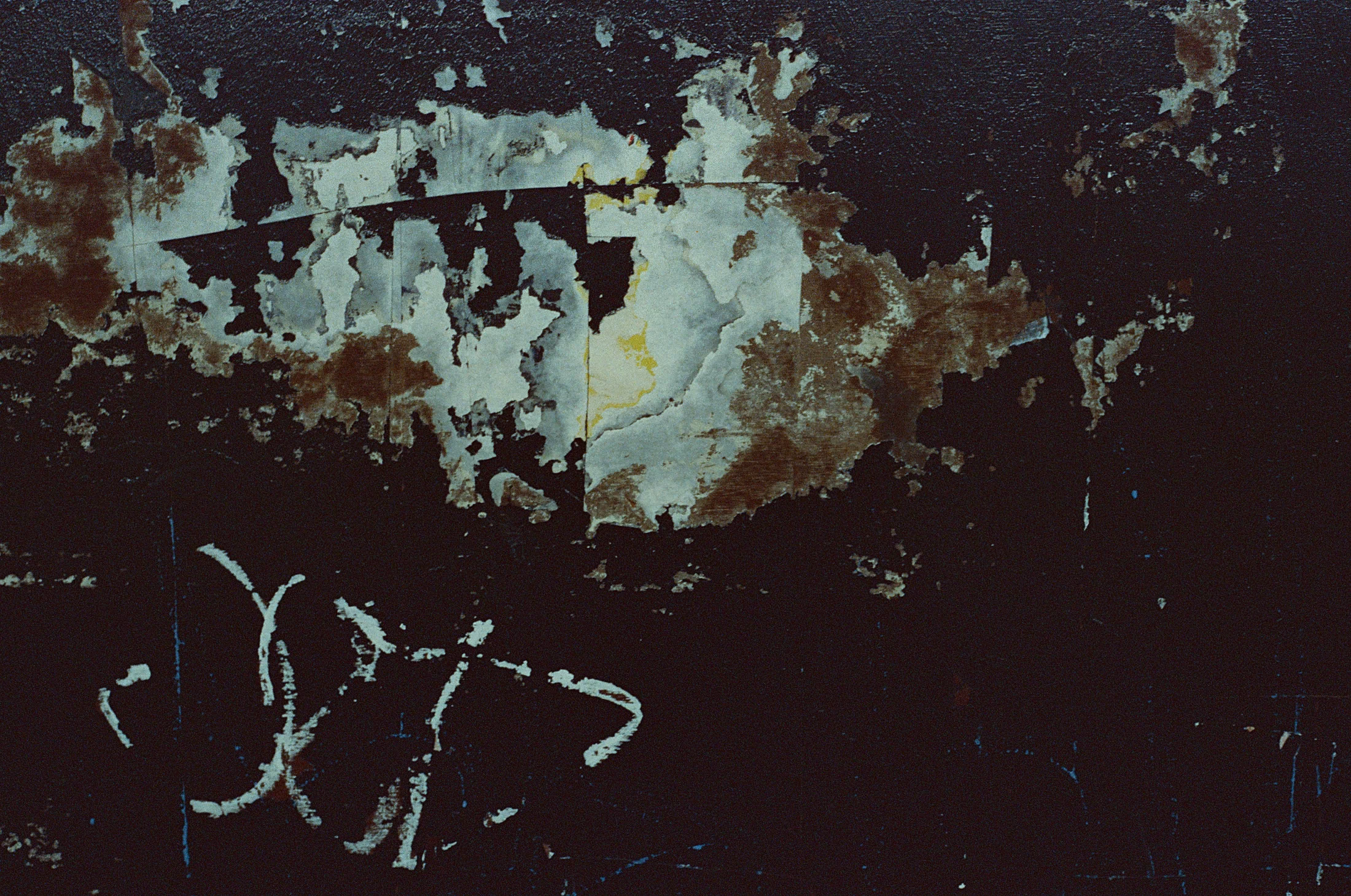 Turquoise paint peeling from a dark surface